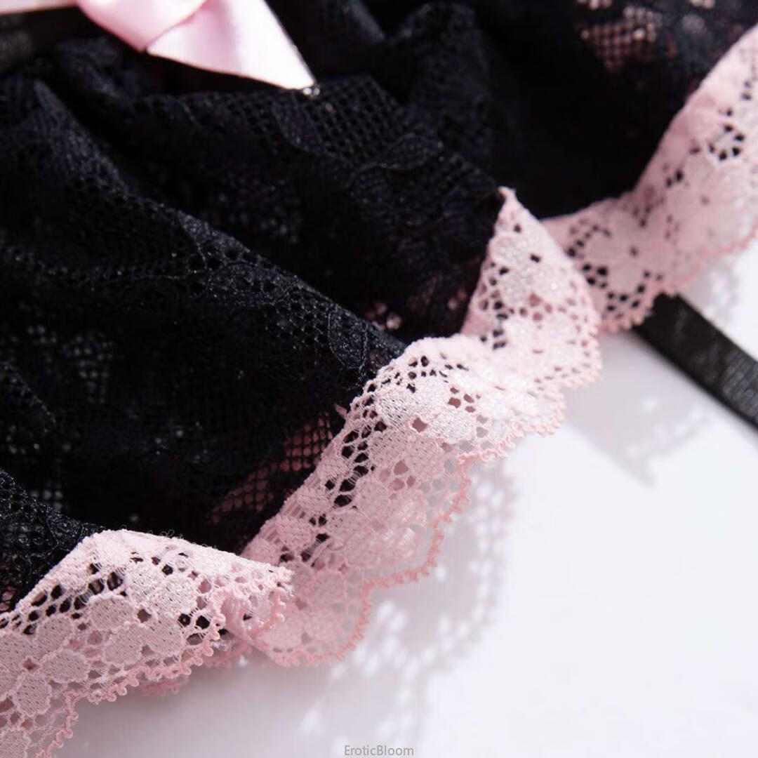 Close-up of black lace corset lingerie set with pink bow and ruffled skirt trim, showcasing French maid style and delicate lace details.