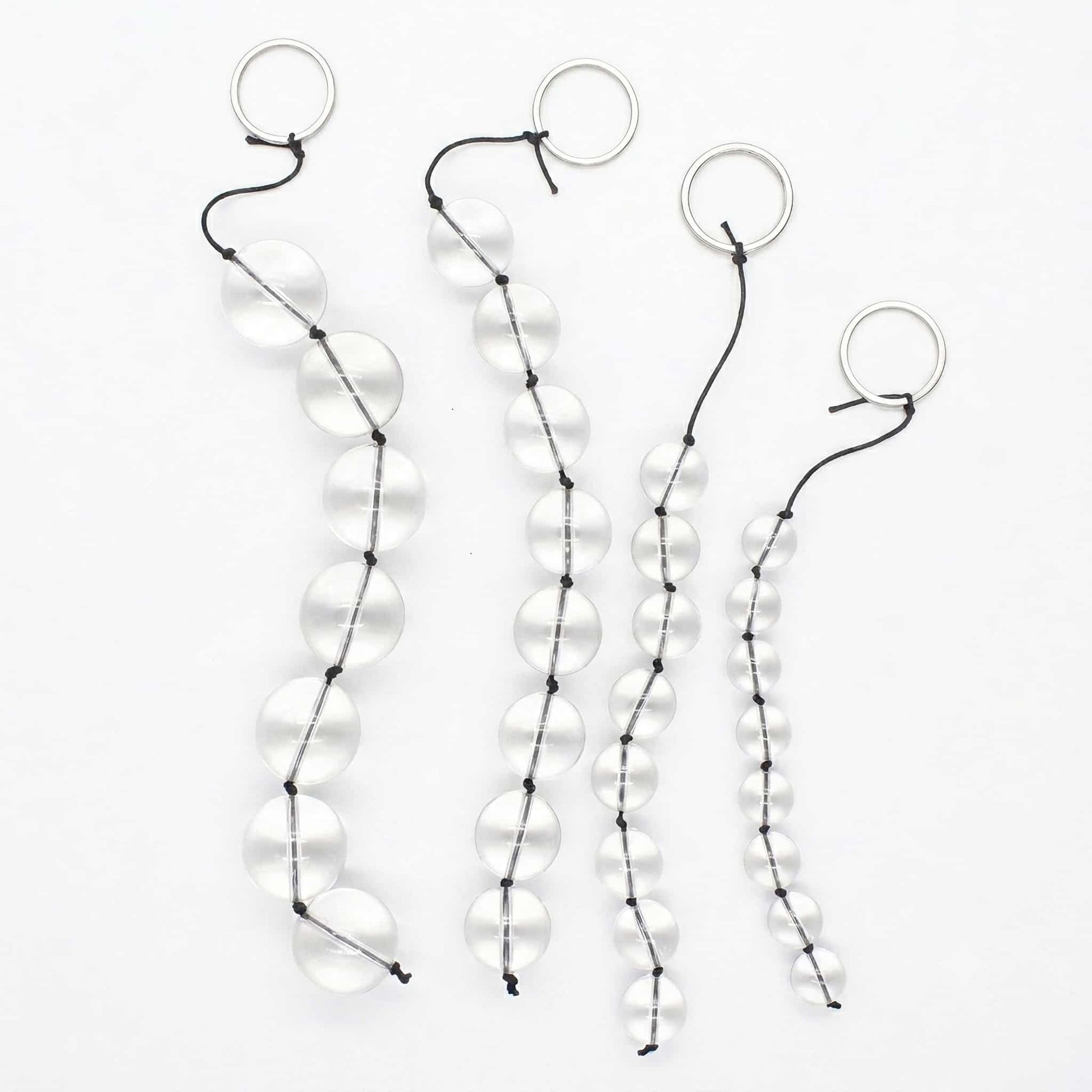 A clean, crisp photo on a white background showing the entire glass linking bead strand. It is arranged in an S-shape, emphasizing its rounded glass beads and stainless steel rings. The beads are crystal clear in the soft lighting, showing off their smooth texture. Photographed from a slightly higher angle for a panoramic display.