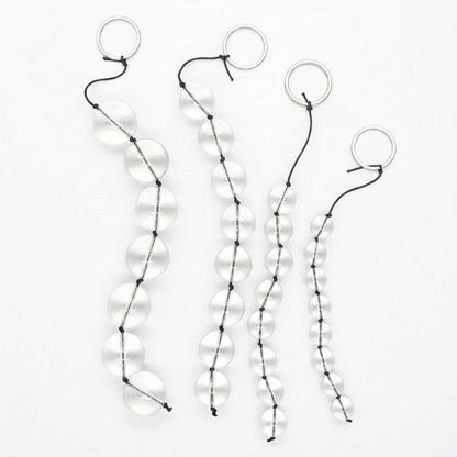 A clean, crisp photo on a white background showing the entire glass linking bead strand. It is arranged in an S-shape, emphasizing its rounded glass beads and stainless steel rings. The beads are crystal clear in the soft lighting, showing off their smooth texture. Photographed from a slightly higher angle for a panoramic display.