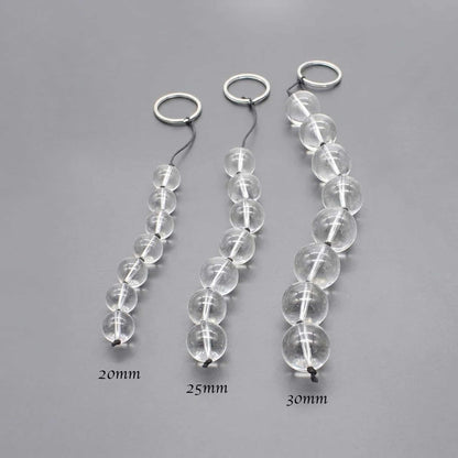 Demonstrate the gradation of pulled glass beads from the smallest to the largest size. Lining up four beads (e.g., 20mm, 25mm, 30mm) and shooting them at an angle highlights the difference in size. The background is a clean gray to make the beads stand out.