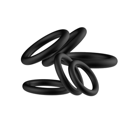 A stacked and intertwined pile of six matte black silicone cock rings on a pure white background, highlighting their smooth texture and seamless design.