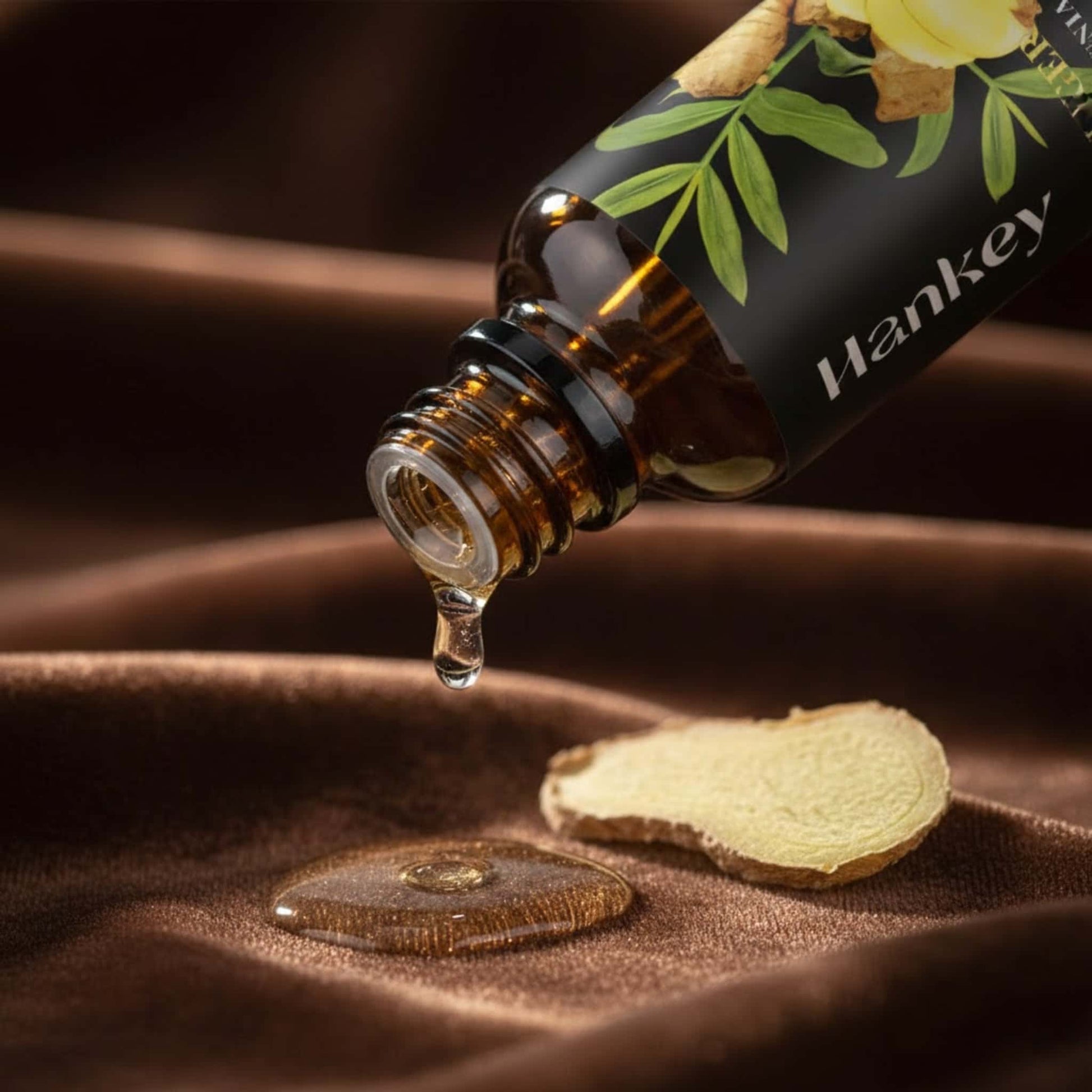 Macro shot of Ginger essential oil dripping from the bottle neck onto luxurious deep brown velvet fabric, emphasizing its rich texture and dropper dispenser.