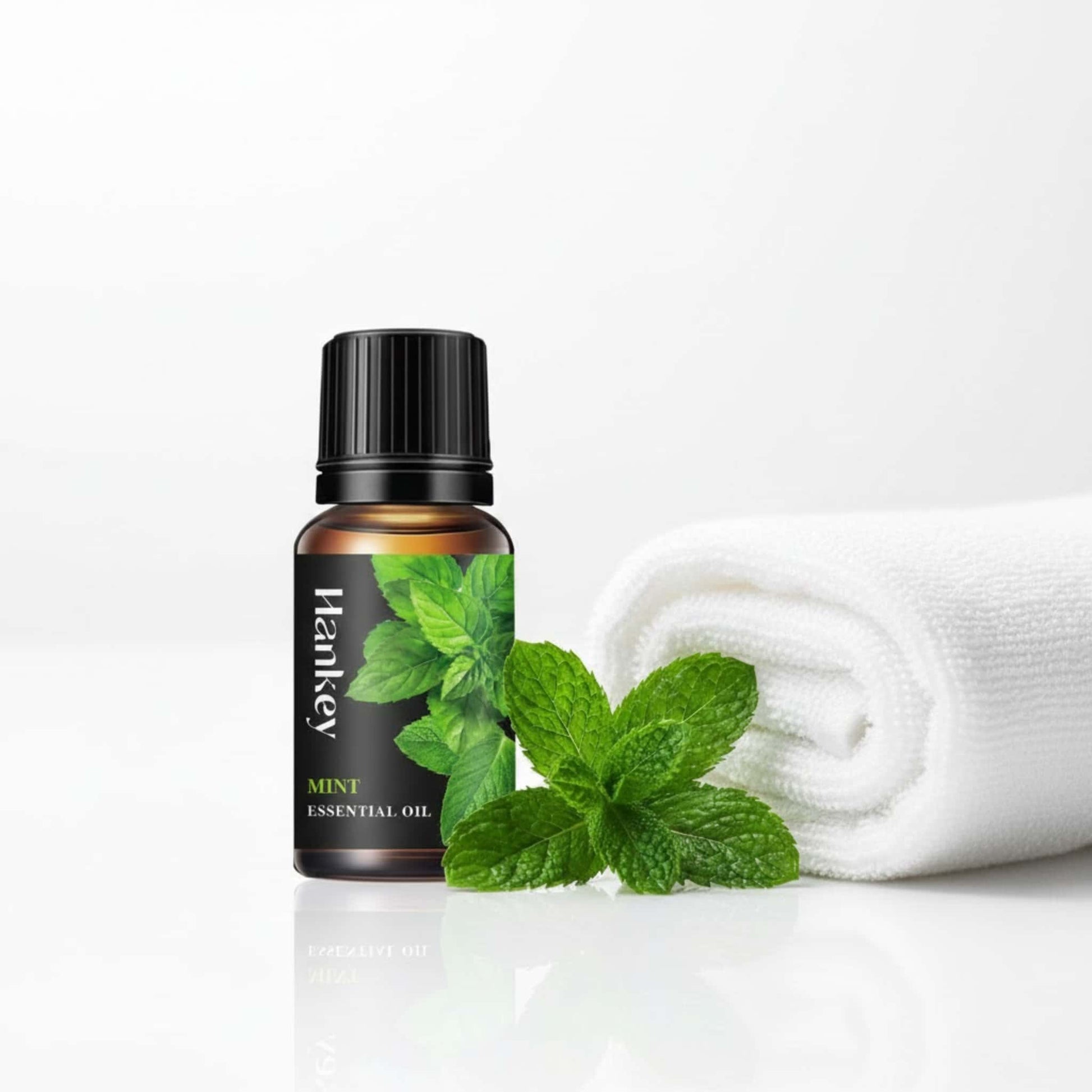 Mint essential oil bottle with fresh mint leaves and a clean towel, highlighting its refreshing and purifying qualities for enhanced intimacy.